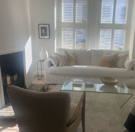 Light-filled drawing room with white sofa, shutters and glass coffee table